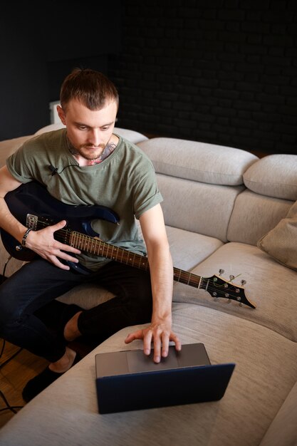 Homme jouant de la guitare à la maison