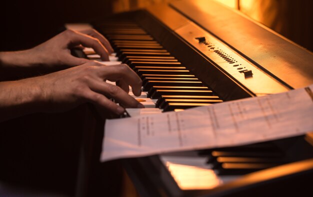 L'homme joue les notes sur le piano, gros plan, beau fond de couleur, le concept d'activité musicale