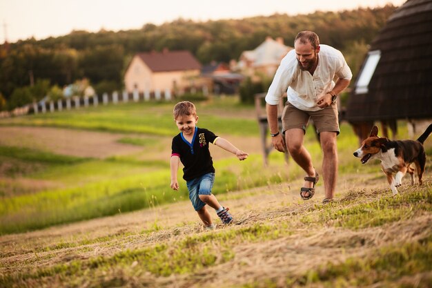 L&#39;homme joue avec son fils et un chien sur le terrain