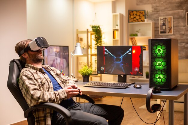 Homme de joueur professionnel utilisant un casque VR pour jouer sur un PC puissant tard dans la nuit dans son salon