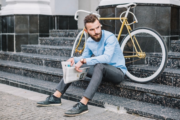 Homme avec journal assis sur les escaliers