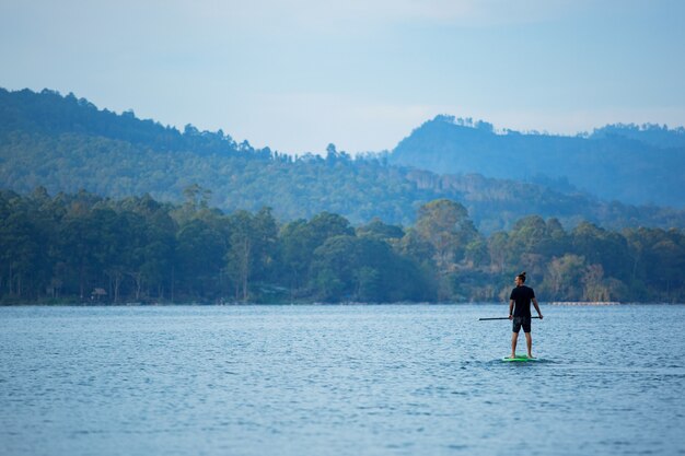 Un homme sur le lac monte une planche de sup.