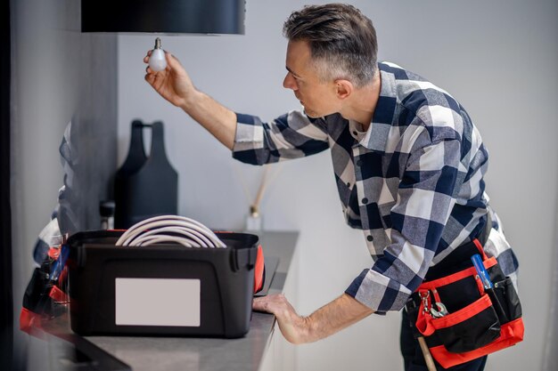 Homme avec lampe dans la main tendue près de la hotte de cuisine