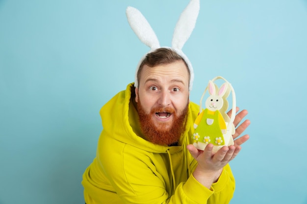 Homme de lapin de Pâques avec des émotions vives sur fond bleu studio