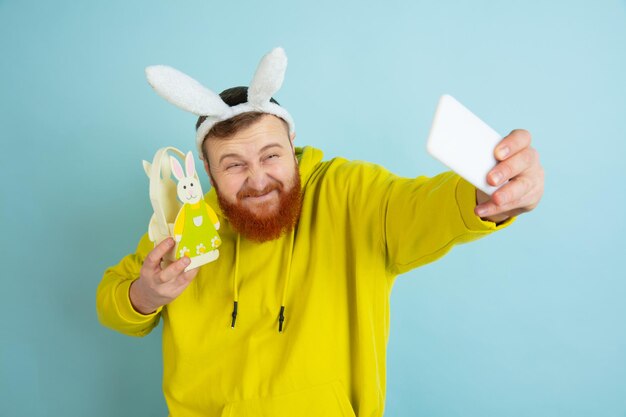 Homme de lapin de Pâques avec des émotions vives sur fond bleu studio