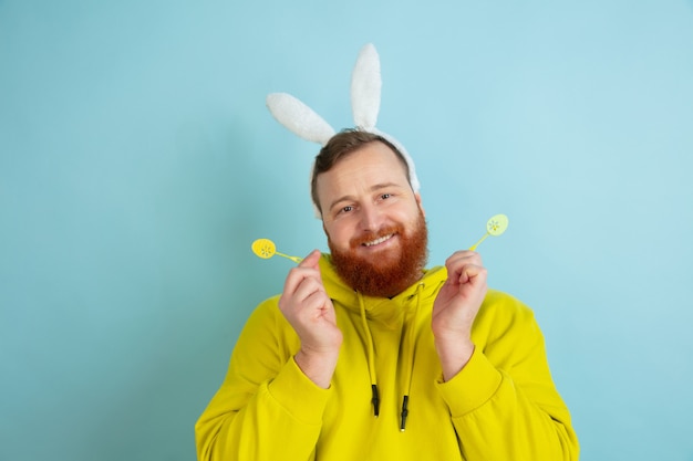 Homme de lapin de Pâques avec des émotions vives sur fond bleu studio