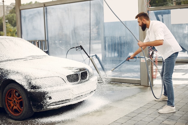 Homme lave sa voiture dans une station de lavage