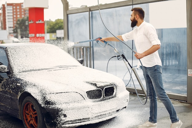 Homme lave sa voiture dans une station de lavage