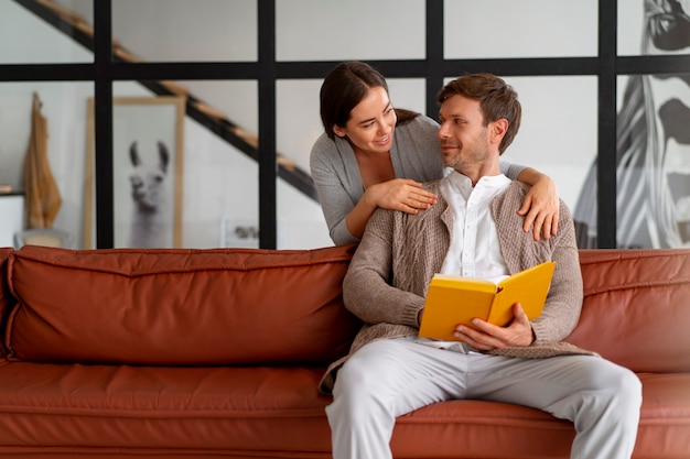 Photo gratuite un homme lisant un livre avec sa femme à côté de lui.
