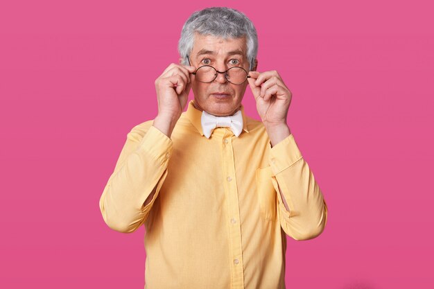 Homme avec des lunettes arrondies noires sur le bout du nez.