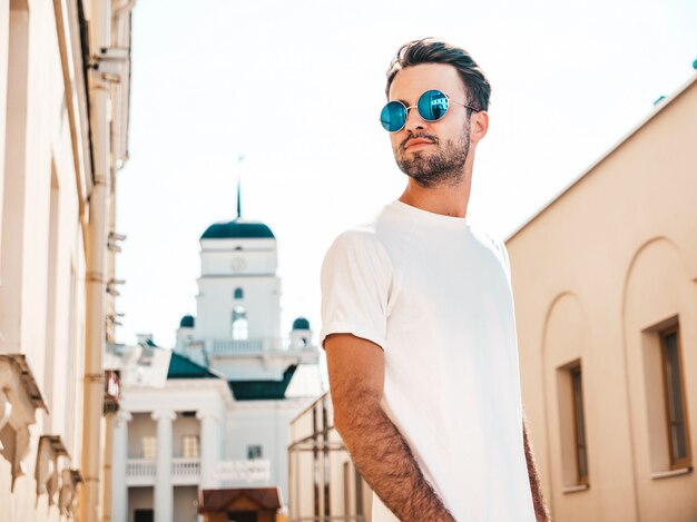 Homme avec des lunettes de soleil portant un t-shirt blanc posant