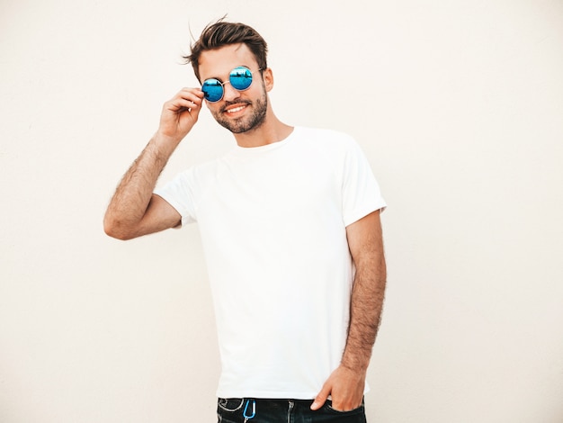Homme avec des lunettes de soleil portant un t-shirt blanc posant