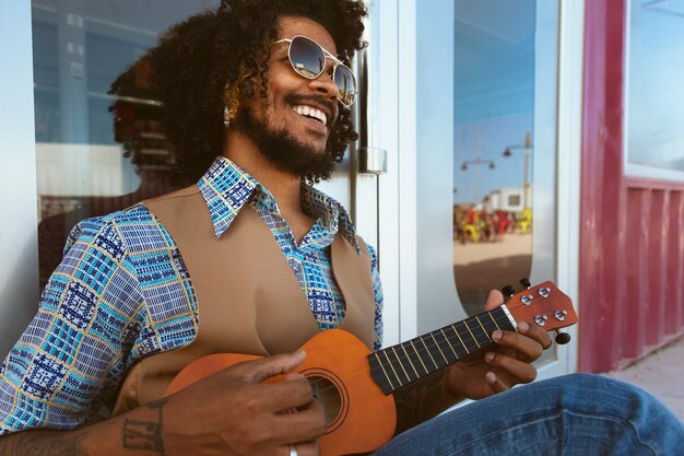 Homme avec des lunettes de soleil posant dans un style rétro avec ukulélé