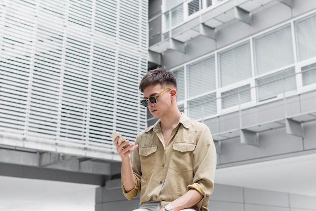 Homme avec des lunettes de soleil regardant le smartphone à l'extérieur