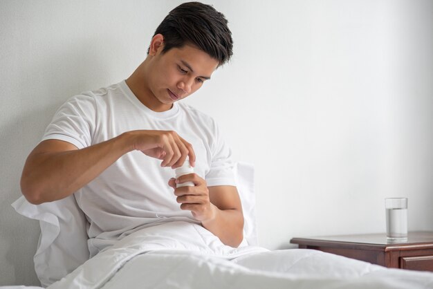 Un homme malade sur le canapé et sur le point de prendre des antibiotiques.