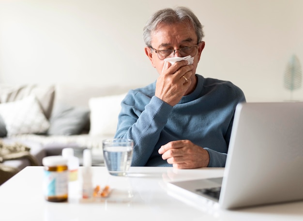 Homme malade de coup moyen avec ordinateur portable