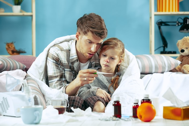 Photo gratuite homme malade avec sa fille à la maison. traitement à domicile. se battre avec une maladie. santé médicale. la vie de la famille. l'hiver, la grippe, la santé, la douleur, la parentalité, le concept de relation. détente à la maison