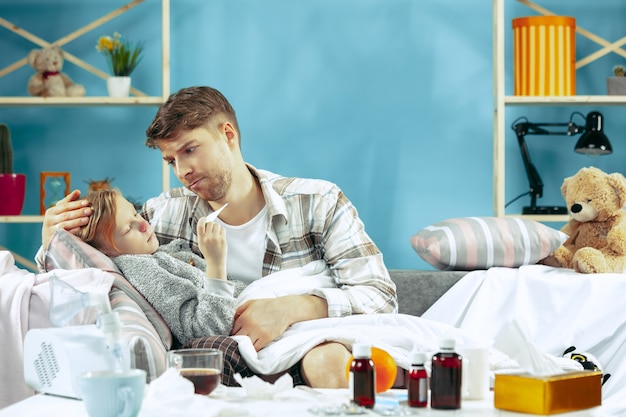 Homme malade avec sa fille à la maison. Traitement à domicile. Se battre avec une maladie. Santé médicale. La vie de la famille. L'hiver, la grippe, la santé, la douleur, la parentalité, le concept de relation. Détente à la maison