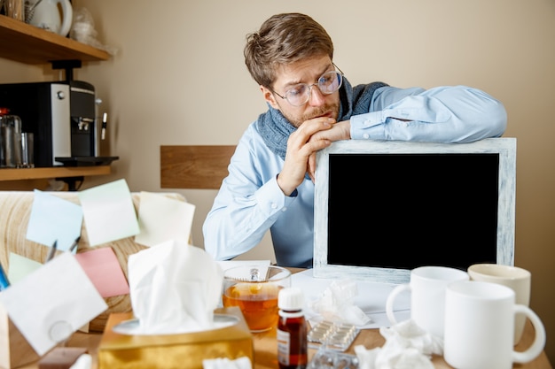 Homme malade tout en travaillant au bureau souffrant de grippe saisonnière.