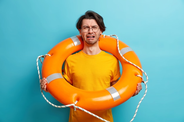 Photo gratuite un homme malheureux de race blanche apprend à nager des poses avec une bouée de sauvetage se prépare pour un voyage de croisière