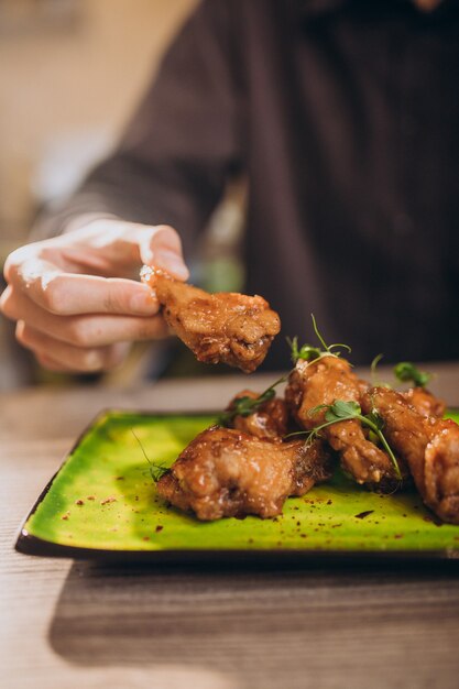 Homme mangeant du poulet frit avec sauce dans un café