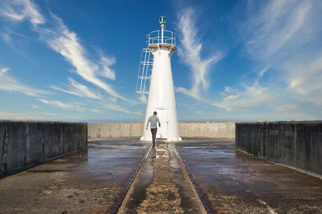 Homme marchant vers le phare à East London, Afrique du Sud.