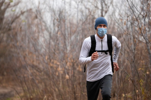 Photo gratuite homme avec masque facial dans les bois en cours d'exécution