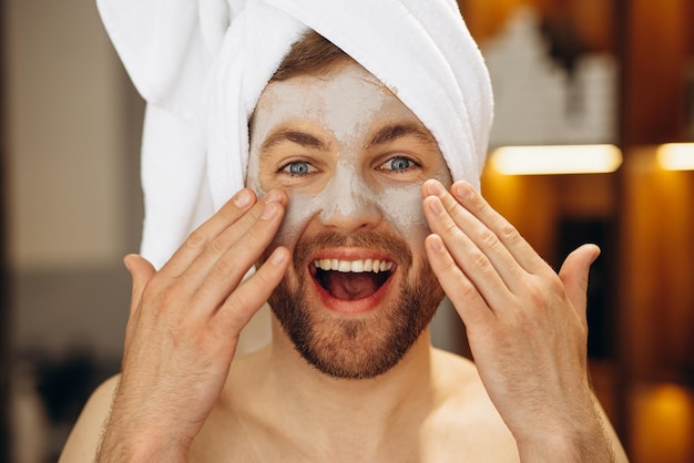 Homme avec masque hydratant et serviette sur la tête