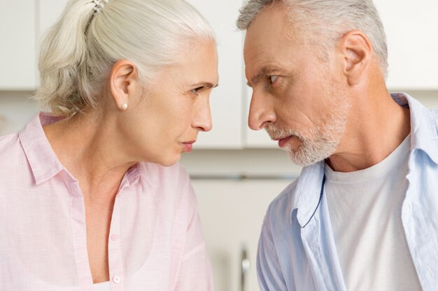 Homme mature en colère, debout près de femme sérieuse mature