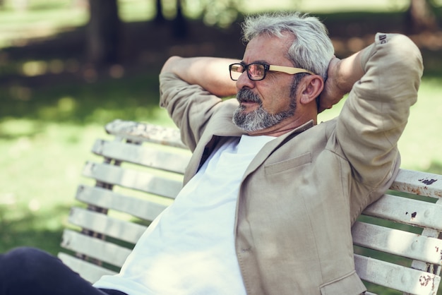 Photo gratuite un homme mature pensif assis sur un banc dans un parc urbain.