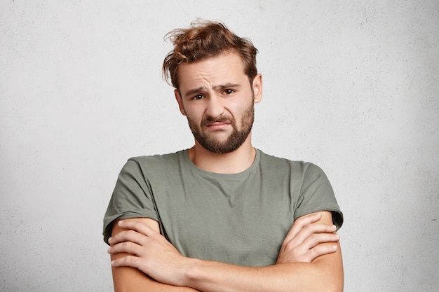 Un homme mécontent avec barbe et moustache fronce le visage, exprime l'hésitation et l'inquiétude,