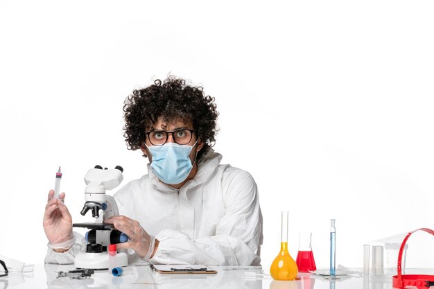 homme médecin en tenue de protection et masque à l'aide d'un microscope sur blanc