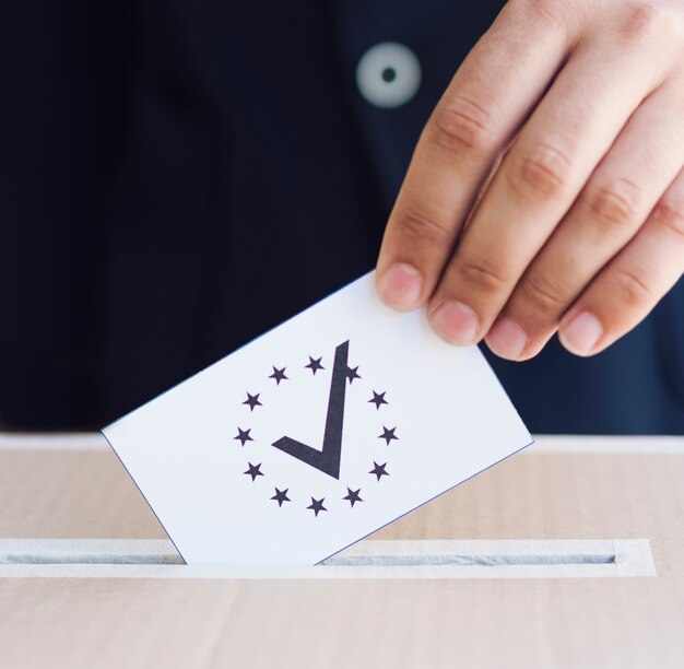 Homme mettant son bulletin de vote dans une boîte close-up