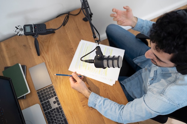 Photo gratuite homme avec microphone et casque exécutant un podcast en studio