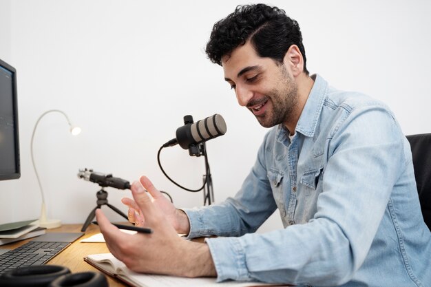 Homme avec microphone exécutant un podcast dans le studio et lisant des journaux