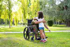 Photo gratuite un homme militaire à la retraite handicapé rencontre et étreint sa petite fille dans le parc. vétéran de guerre ou concept de retour à la maison