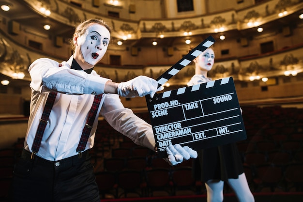 Homme mime tenant un battant devant un artiste mime féminin sur scène