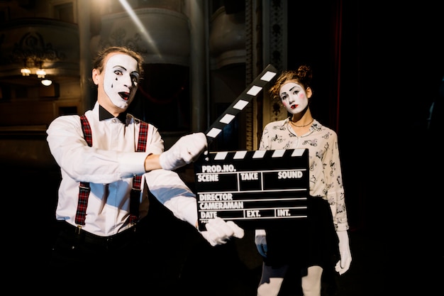 Homme mime tenant un clap devant un artiste mime féminin