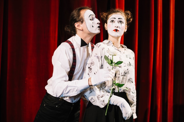 Homme mime tenant une rose blanche devant un mime féminin