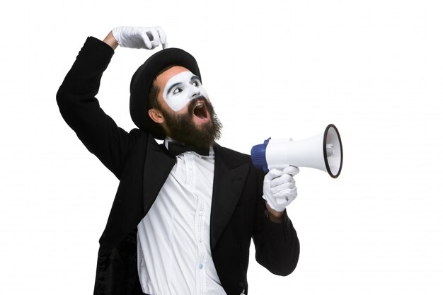 Homme avec un mime visage criant dans un mégaphone