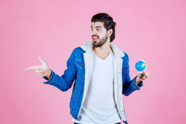 Homme avec un mini globe pointant sur quelqu'un