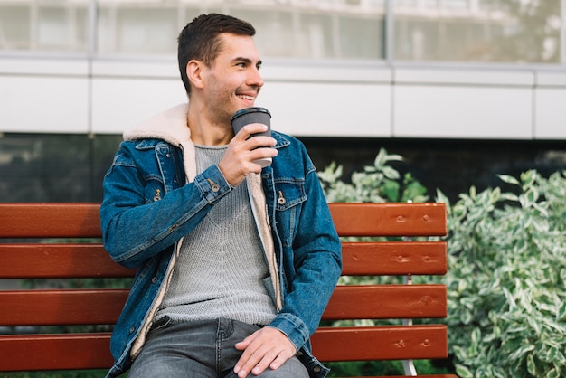 Homme moderne assis sur un banc en milieu urbain