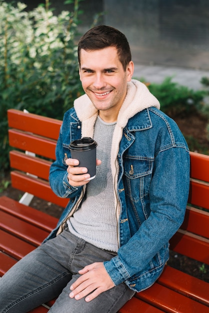 Photo gratuite homme moderne assis sur un banc en milieu urbain