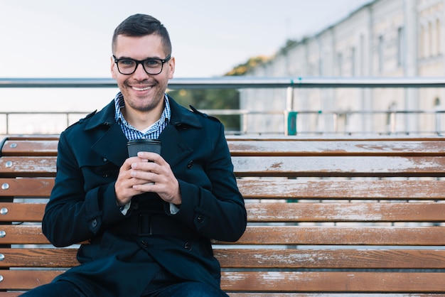 Homme moderne avec café sur banc