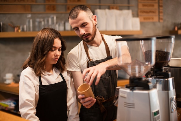 Homme montrant à une femme une tasse avec une machine à café