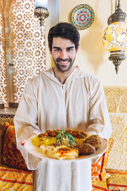 Homme montrant un plat de nourriture arabe