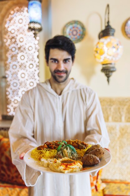 Homme montrant un plat de nourriture arabe