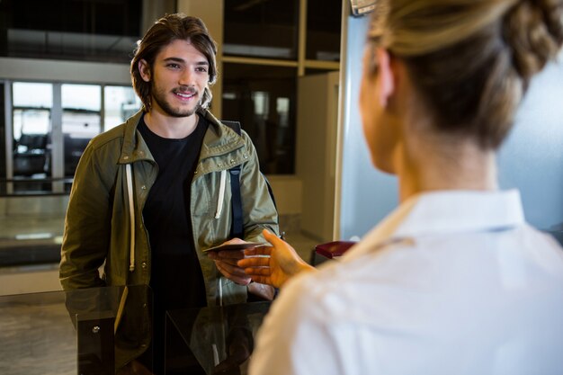 Homme montrant sa carte d'embarquement au comptoir d'enregistrement