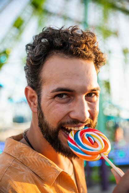 Homme mordant la sucette à la fête foraine