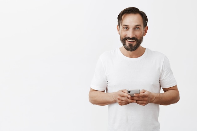 homme mûr barbu posant avec son téléphone